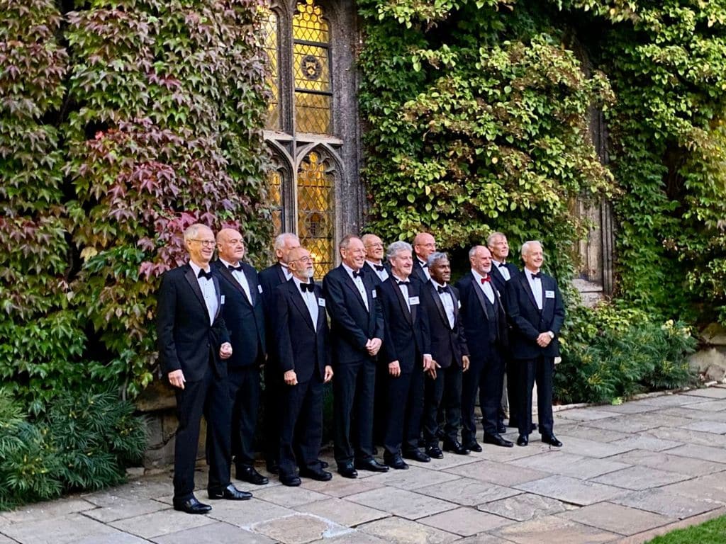 1975 year group in formal dress posing in Front Quad with ivy-covered walls in the background