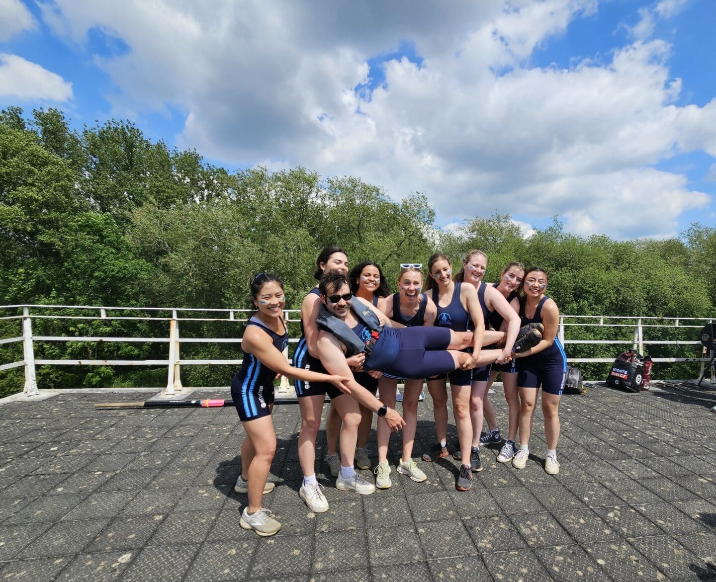 Outdoor photo of W2 crew members posing in kit holding up a crew member