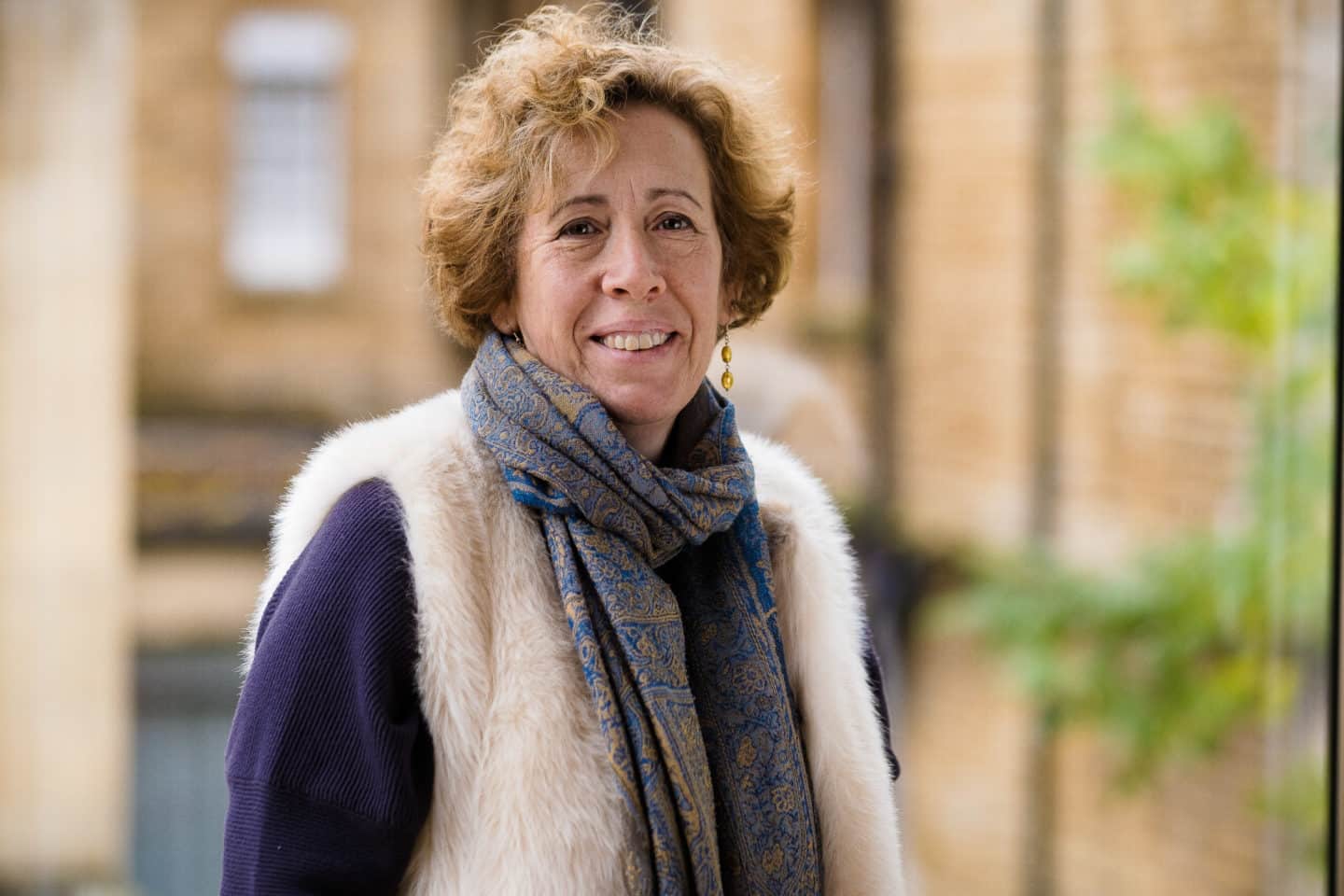 Headshot of Dr Lucy Wooding, a woman in a purple top, white coat and blue and gold scarf