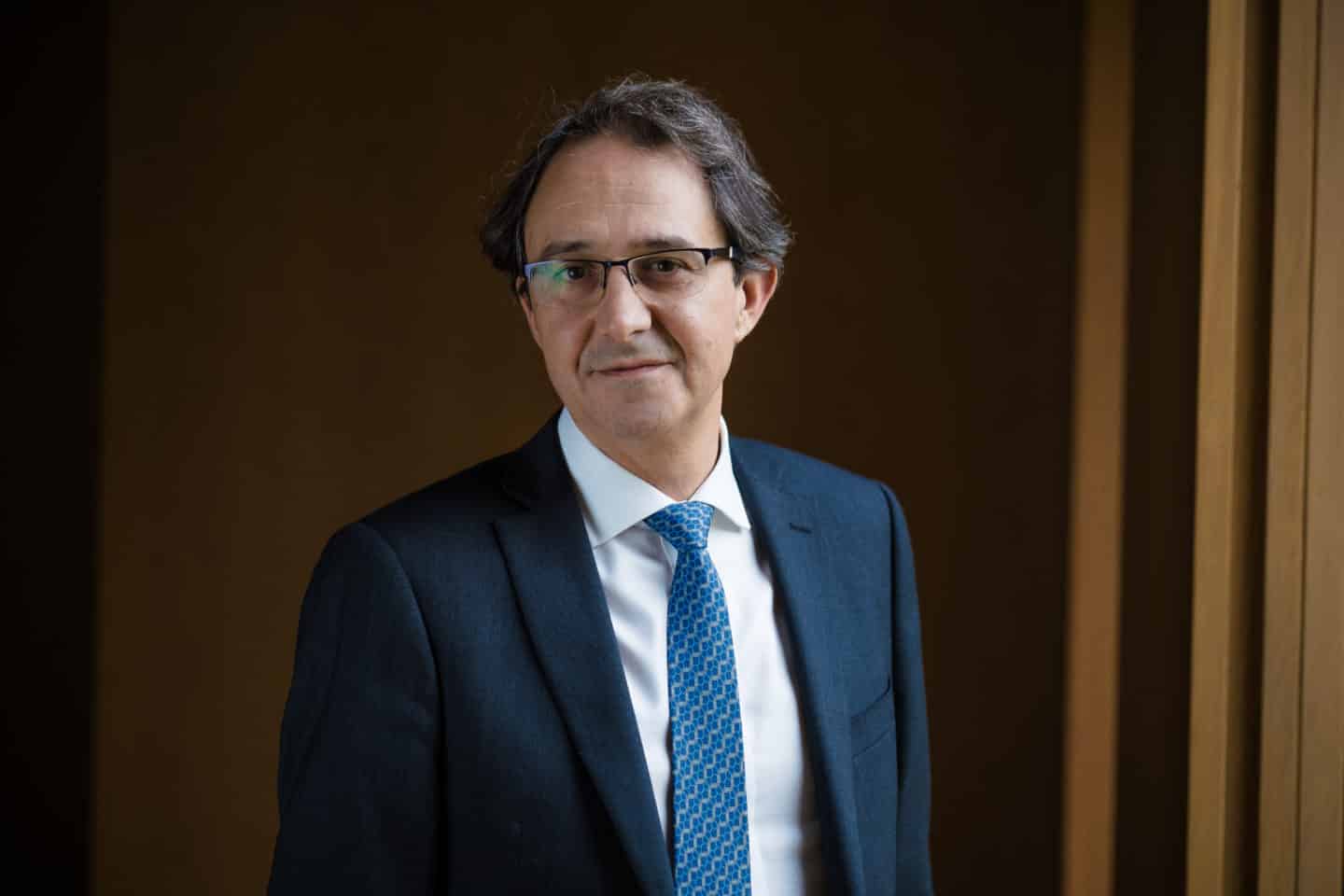 Headshot of Dr Paul Stavrinou, a man in glasses and a blue suit and tie