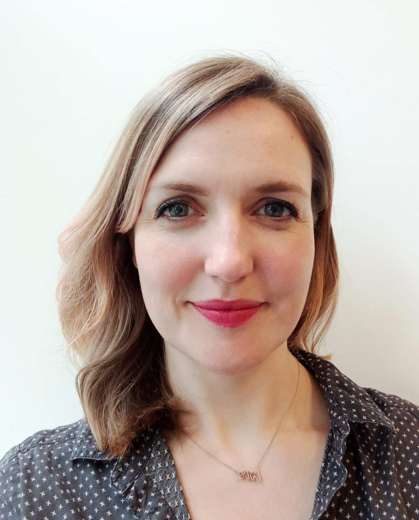 Headshot of Eileen Parkes, a woman with a necklace and a black and white shirt