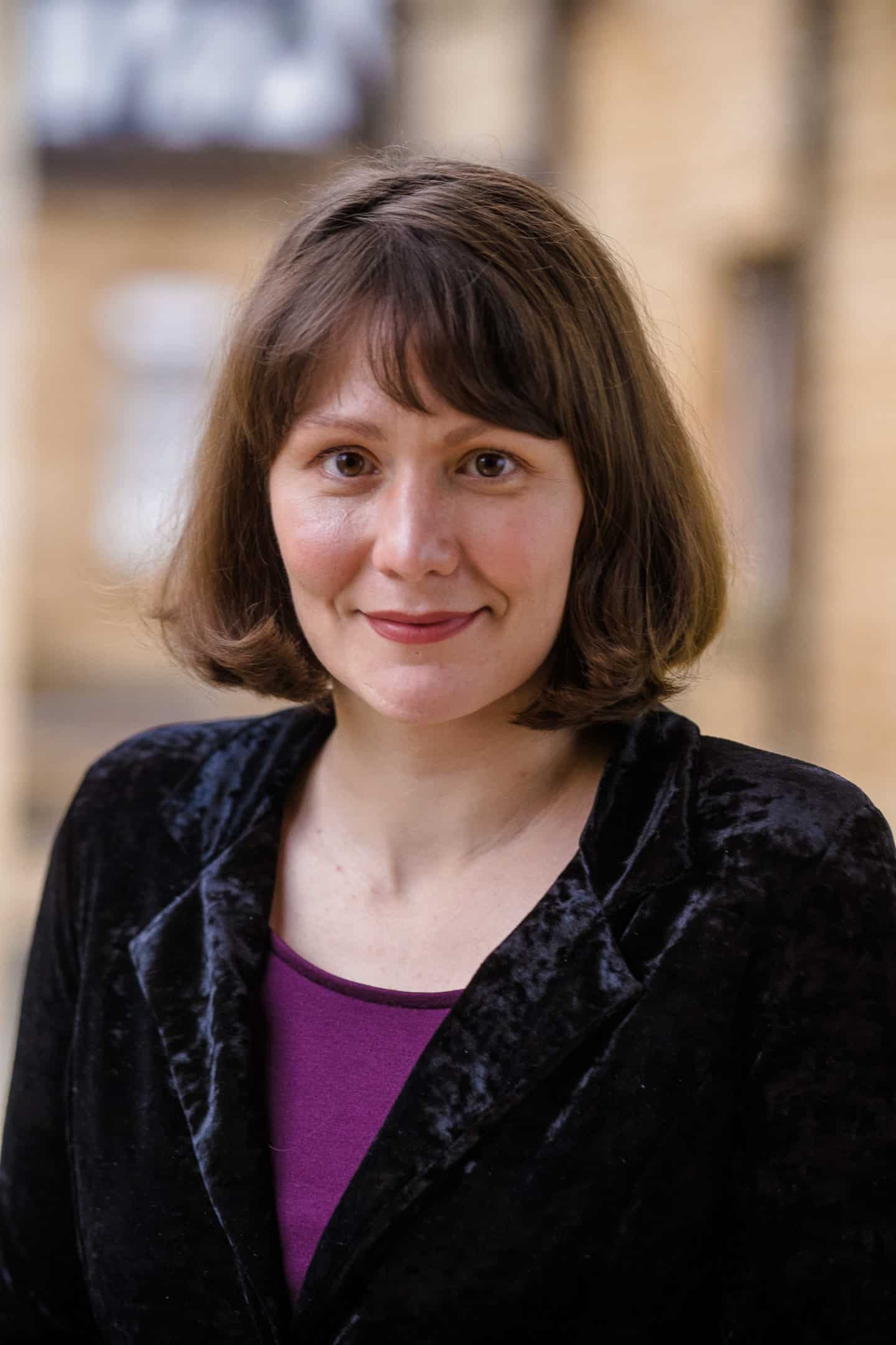 Headshot of Lydia Matthews, a woman in a purple top and dark coat