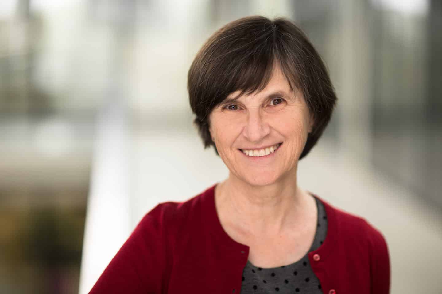 Headshot of Professor Margaret Stevens, a woman in a grey top and red cardigan