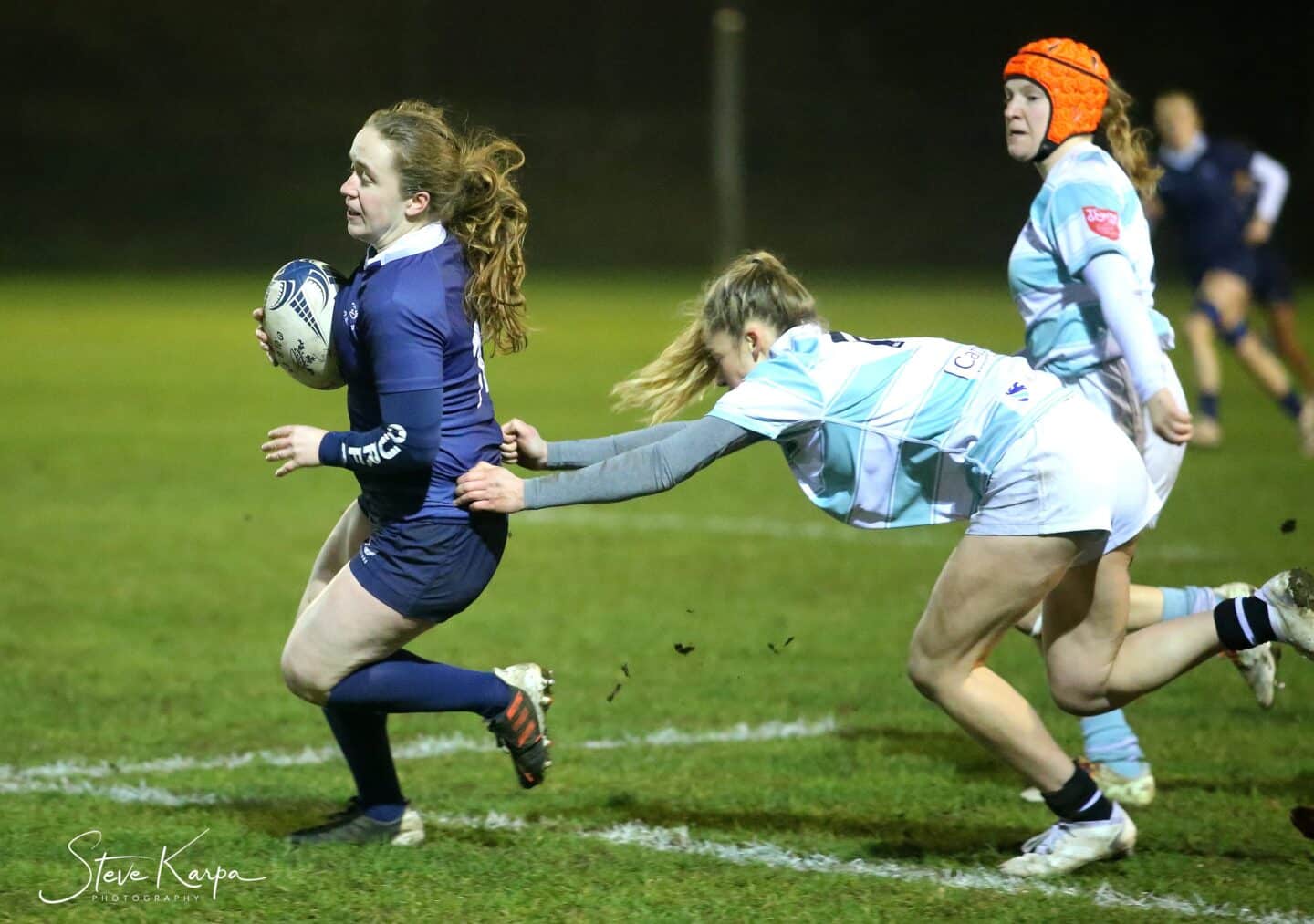 Katie Hains running with th ball with an opposing player reaching for her from behind