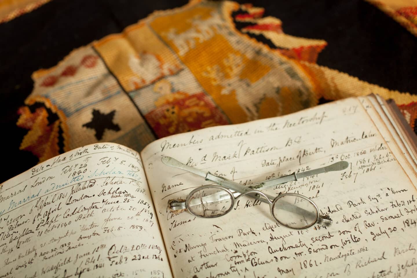 Photo glasses on open book resting on a folded tapestry