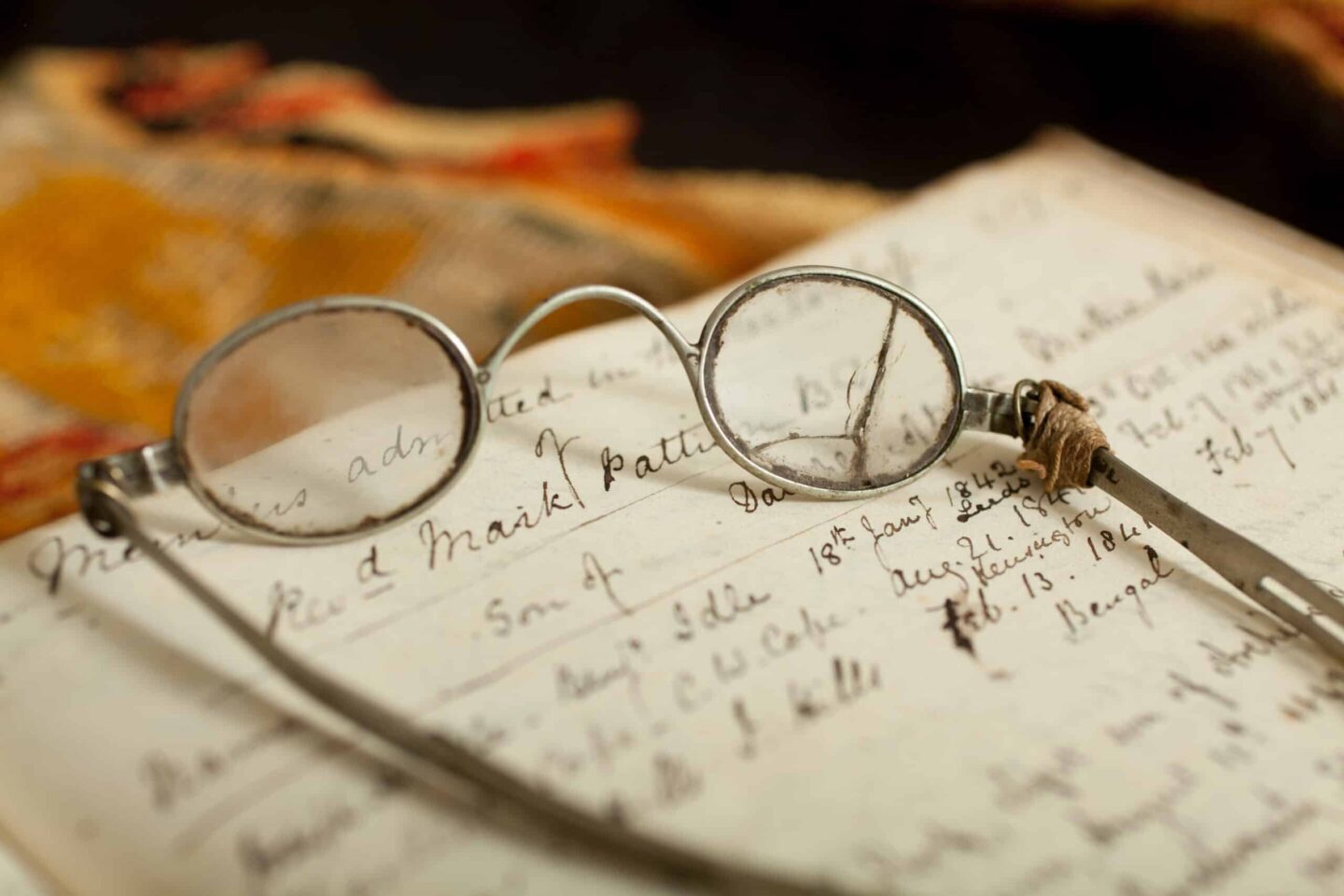 Round spectacles on a note mentioning Mark Pattison