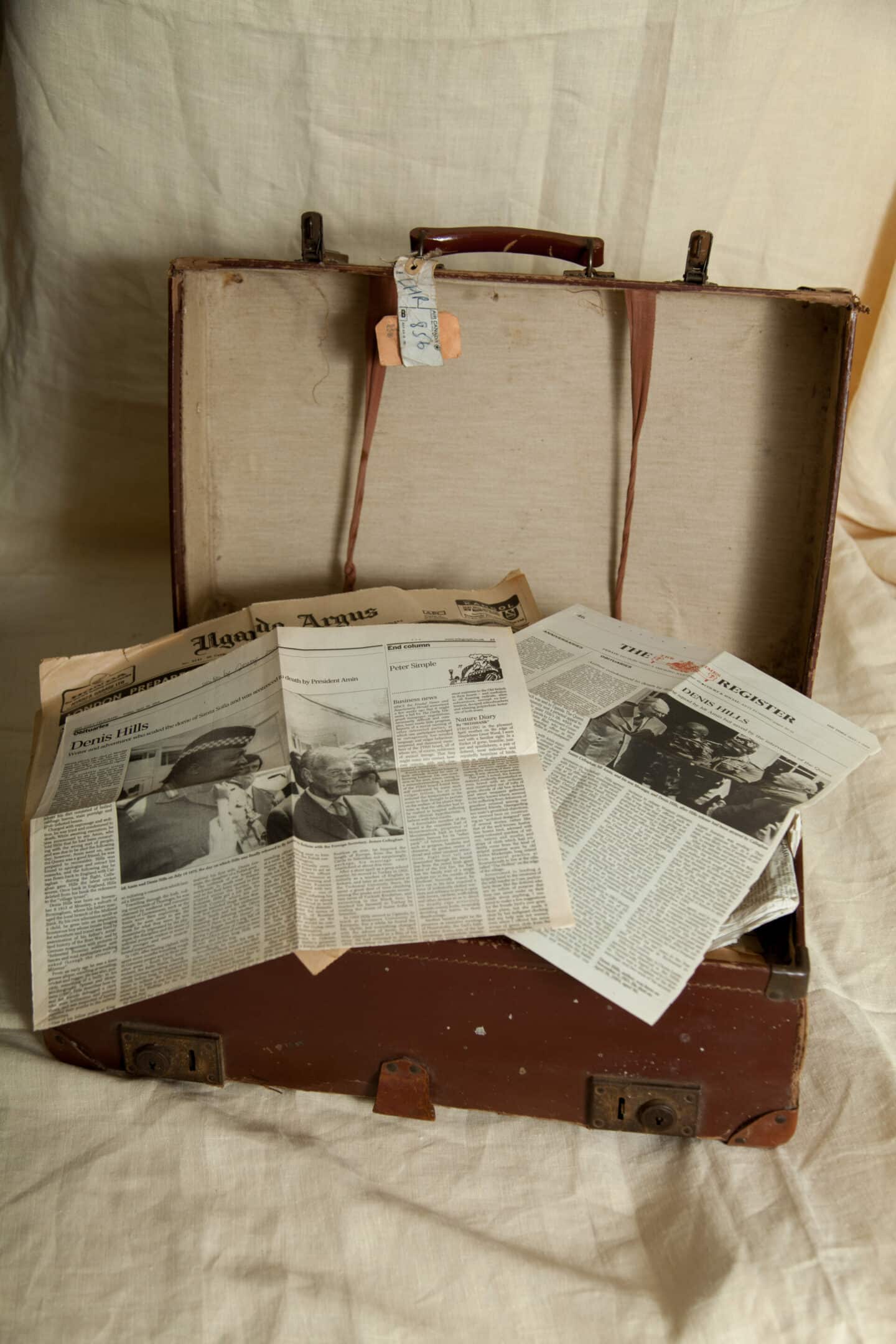 Old news clippings about Denis Hills sitting atop an open suitcase