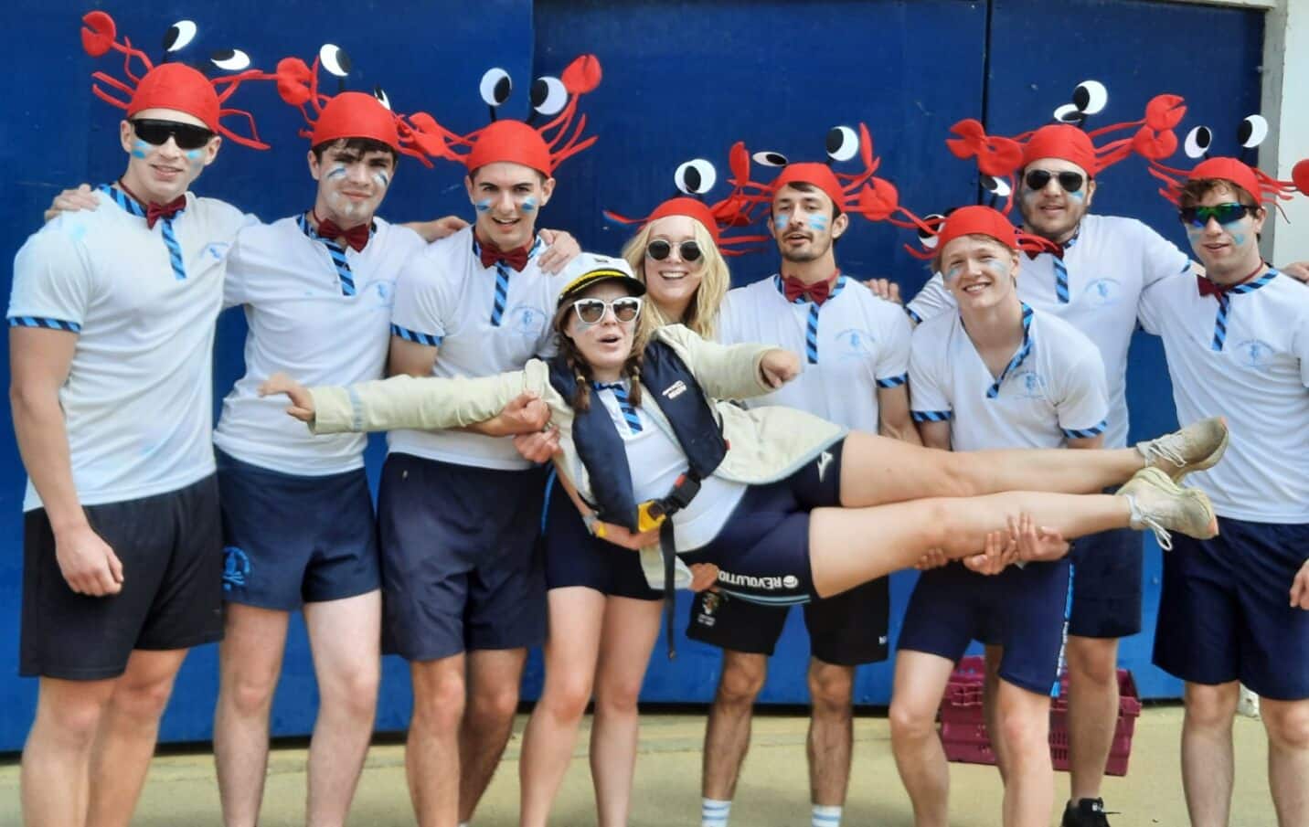 A group of Lincoln College rowers with crab hats holding up their Cox